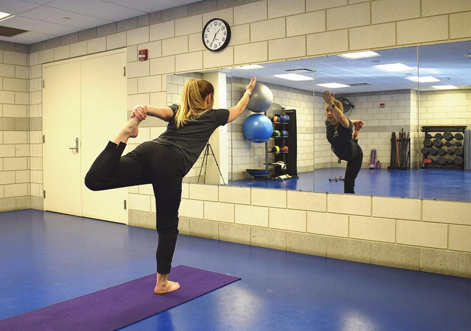 Employee Yoga class instructor demonstrating a standing balance pose