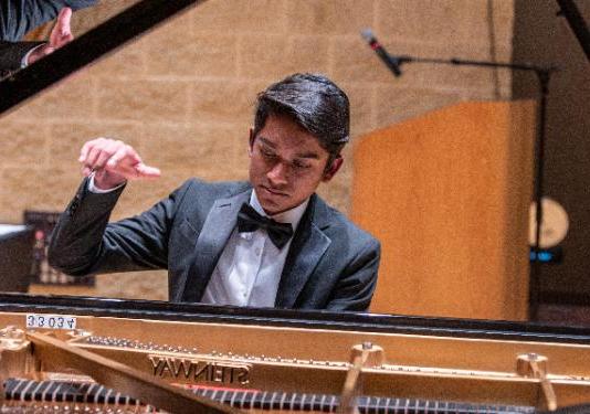 photo of young man playing grand piano