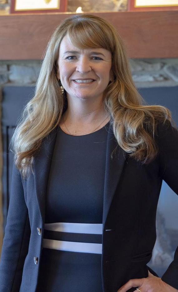 Portrait of Kim Grannan standing in front of a fireplace in the Alumni Center.